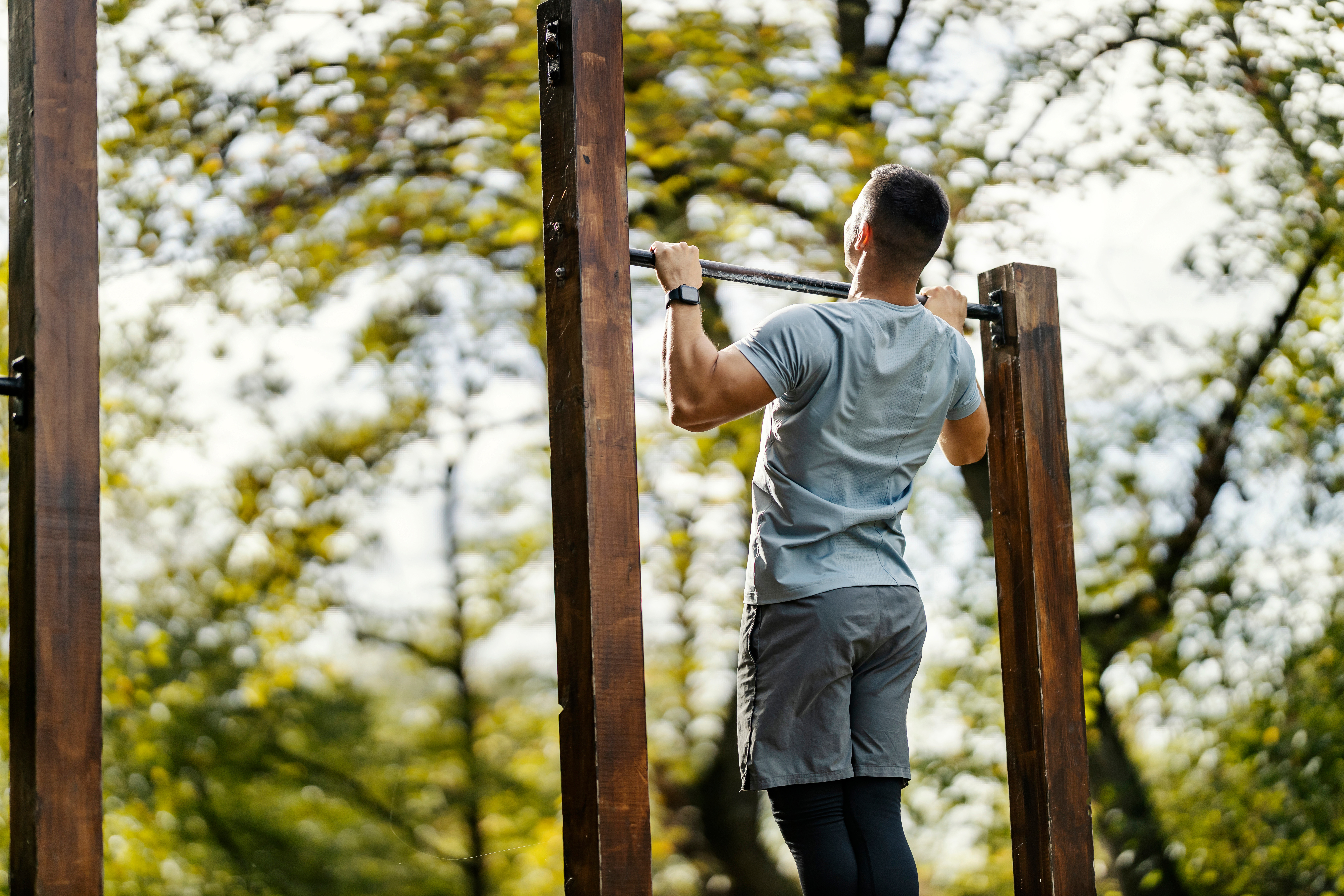 Boy in woods training on calisthenics apparatus
